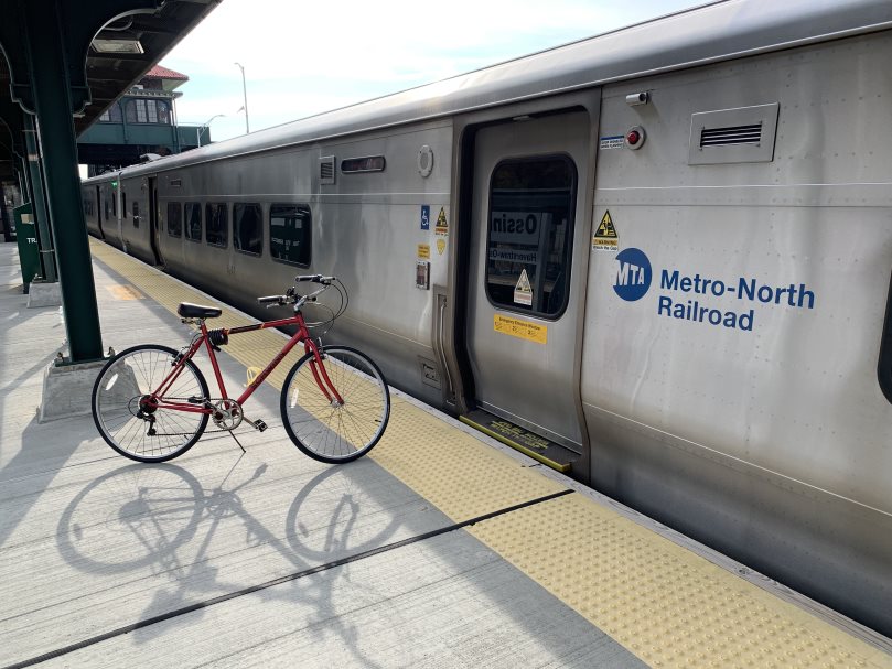 A bike parked on a train platform next to a train car.