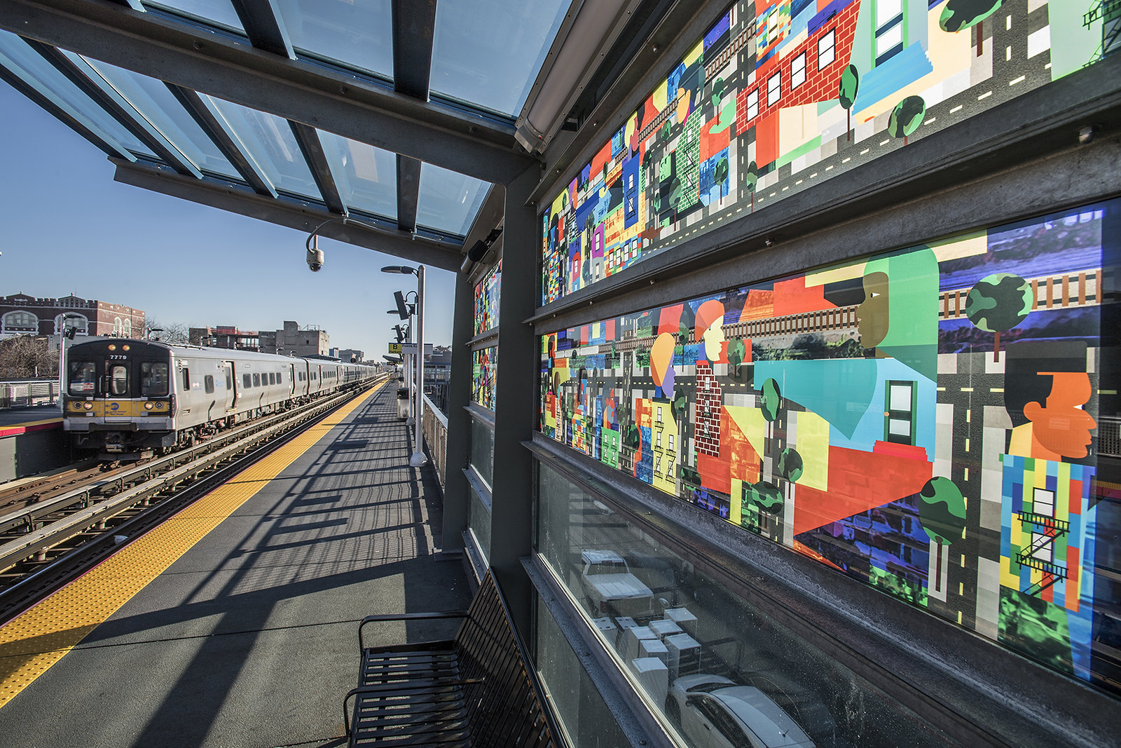 A train station at Nostrand Avenue, with a multicolored glass mosaic on the platform. 