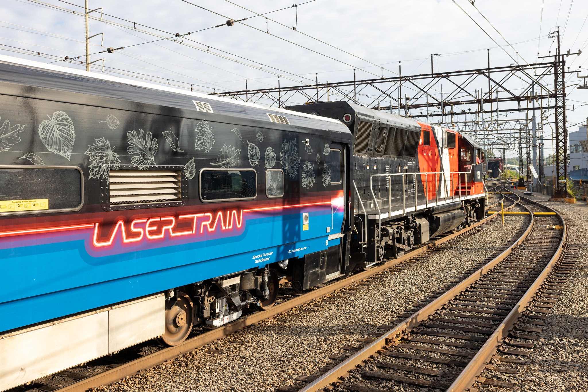A train car with a colorful wrap that says "laser train"