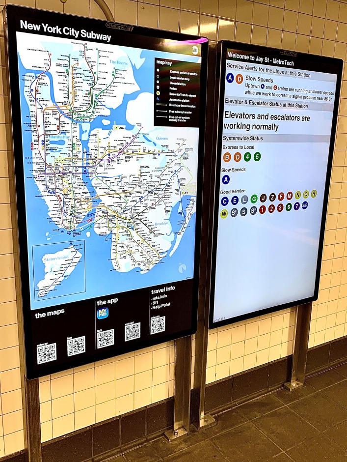 Image shows two large customer information center digital screens. On the left, scren shows subway map. On the right, screen shows service alerts for Jay St-MetroTech station, Elevator and Escalator Status at Bowling Green station, and Systemwide status showing express to local service changes, delays, planned work, and good service. 
