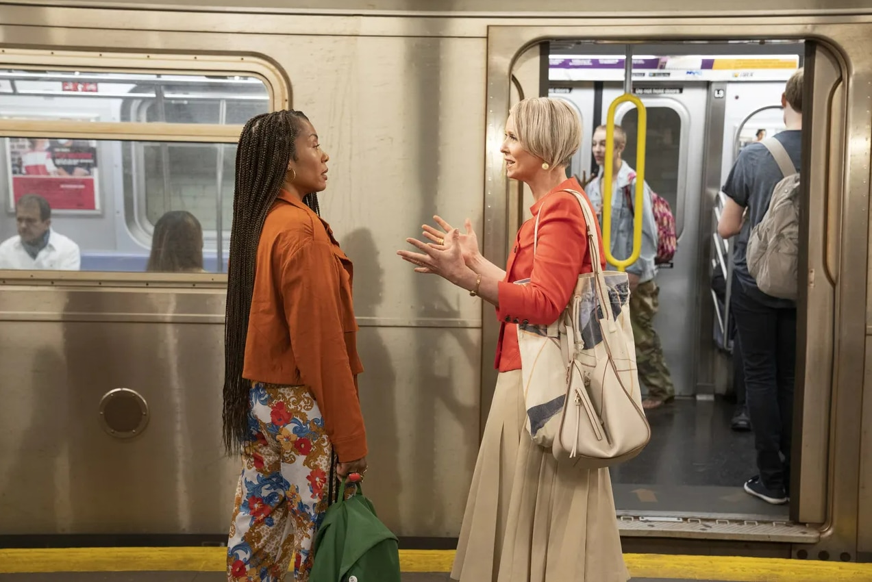 Actors Karyn Pittman and Cynthia Nixon talk on a subway platform in front of a subway car