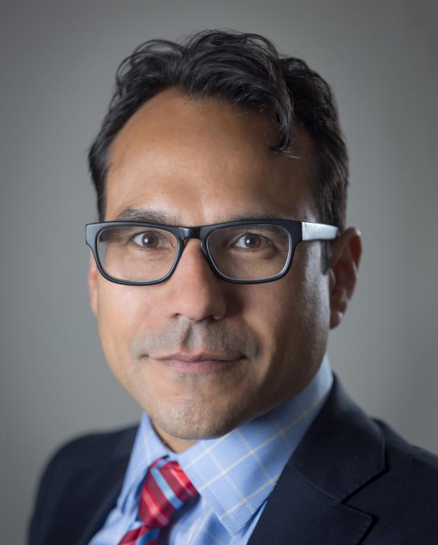 A head shot of Robert Mujica Jr., who looks straight at the camera wearing glasses. 