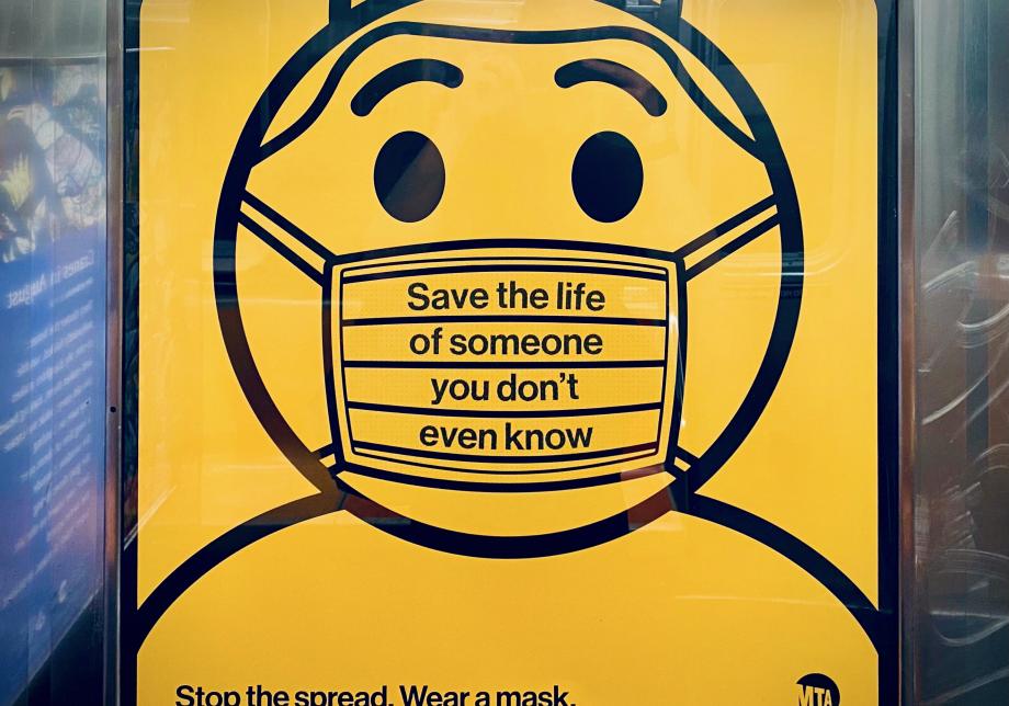 Photograph of an subway ad featuring a illustrated person wearing a mask