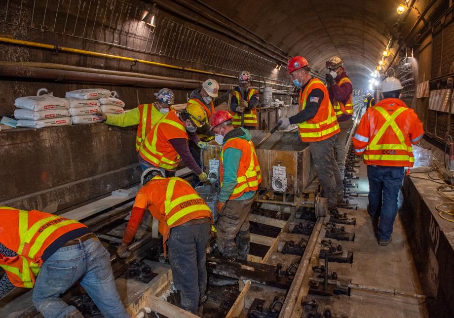Workers pour concrete as part of replacing track in the Rutgers Tunnel
