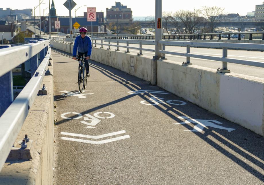 A person on a bicycle rides on a bike path on a bridge.