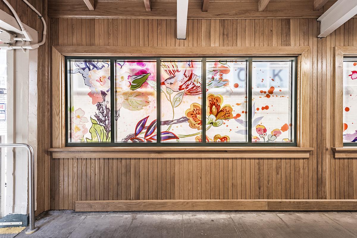A straight on photograph of laminated glass panels. Panels feature painterly flowers, brush strokes, paint splatters and a bird.