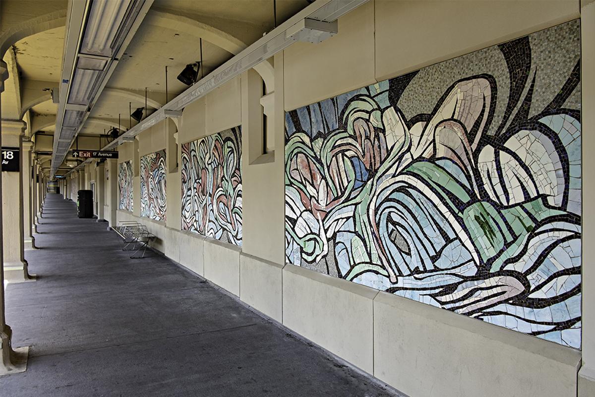 A diagonal, landscape view of 18 Avenue station walls featuring three mosaic panels with predominately red with white, green, and blue artwork details. 