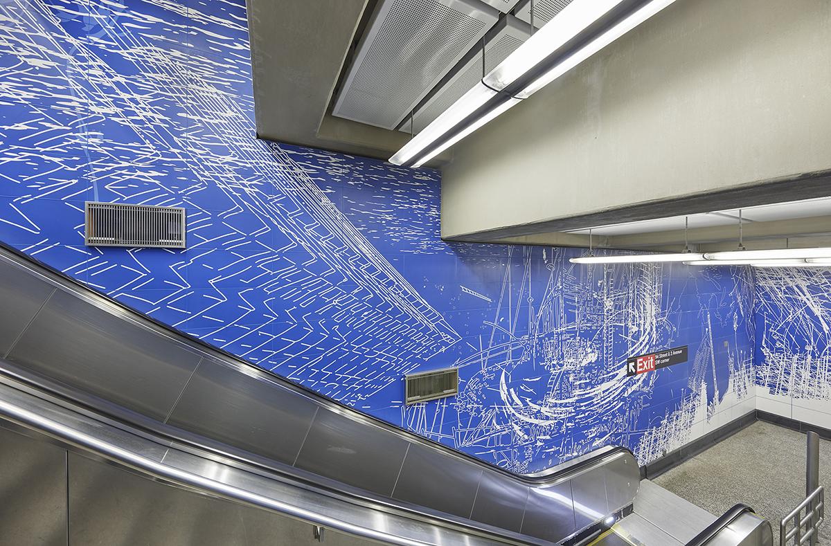 Painted wall tile artwork by Sarah Sze showing abstract drawings and blueprints in blue and white. 