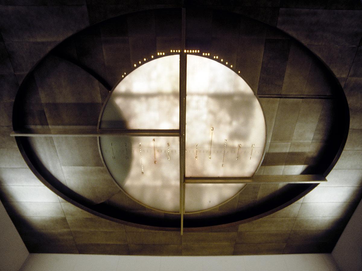 Sculpture in glass and metal by Maya Lin installed in the ceiling with light shining through. 