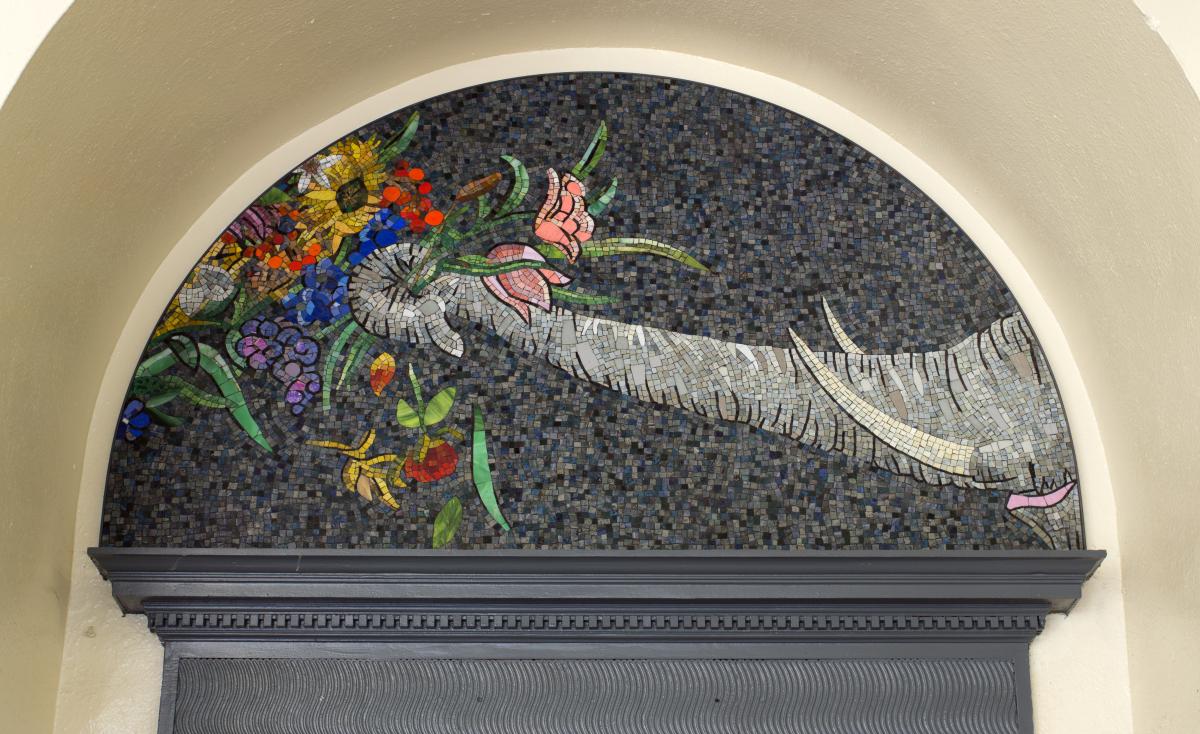 Artwork in glass mosaic, laminated glass and stone by Luisa Caldwell showing flowers and animals on the walls and above the doors.