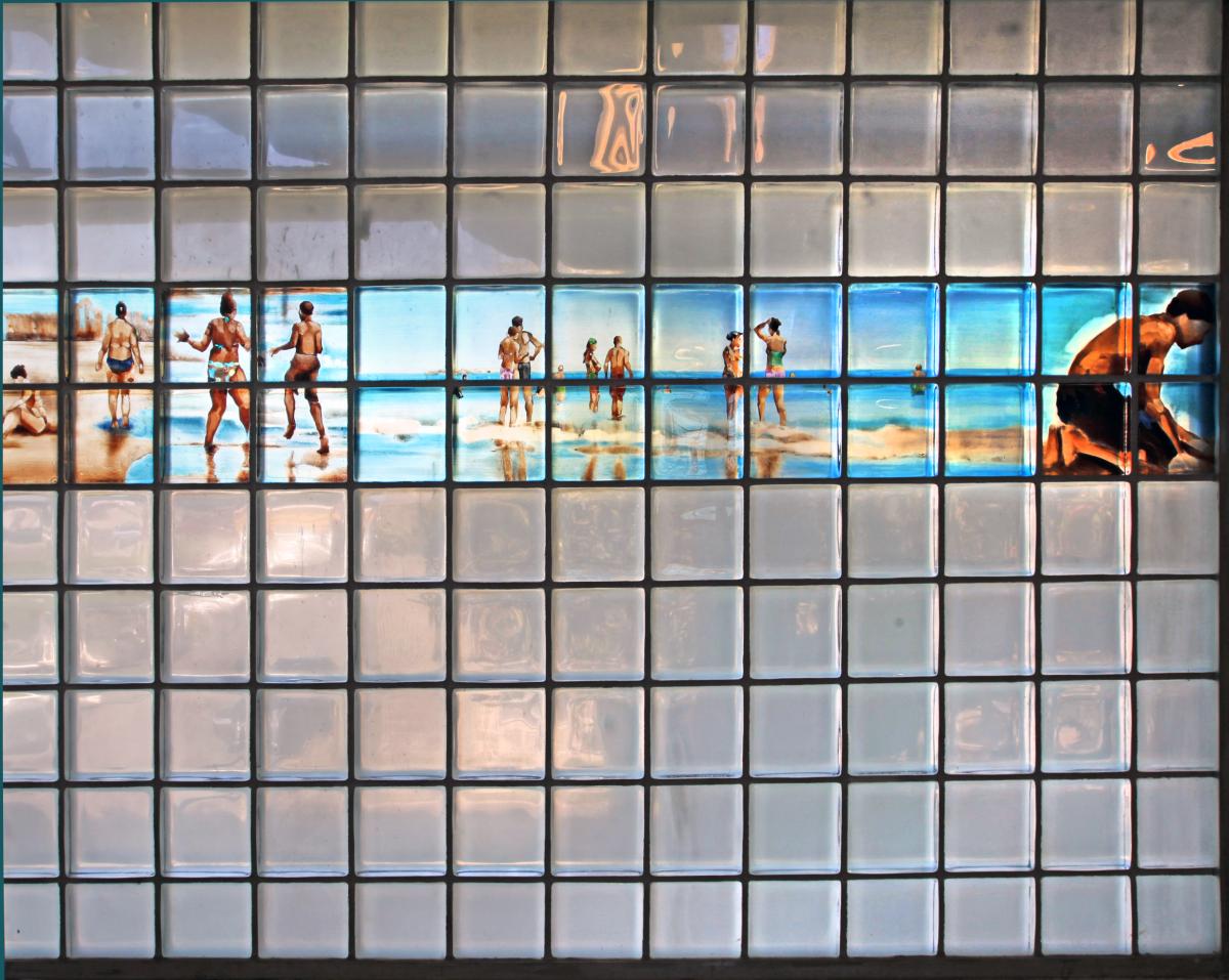 Artwork in glass block by Simon Levenson showing figures at the beach.