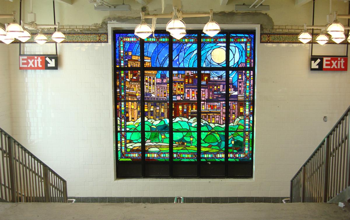 Artwork in faceted glass by William Low showing large colorful day and night city scenes over the stairwells.