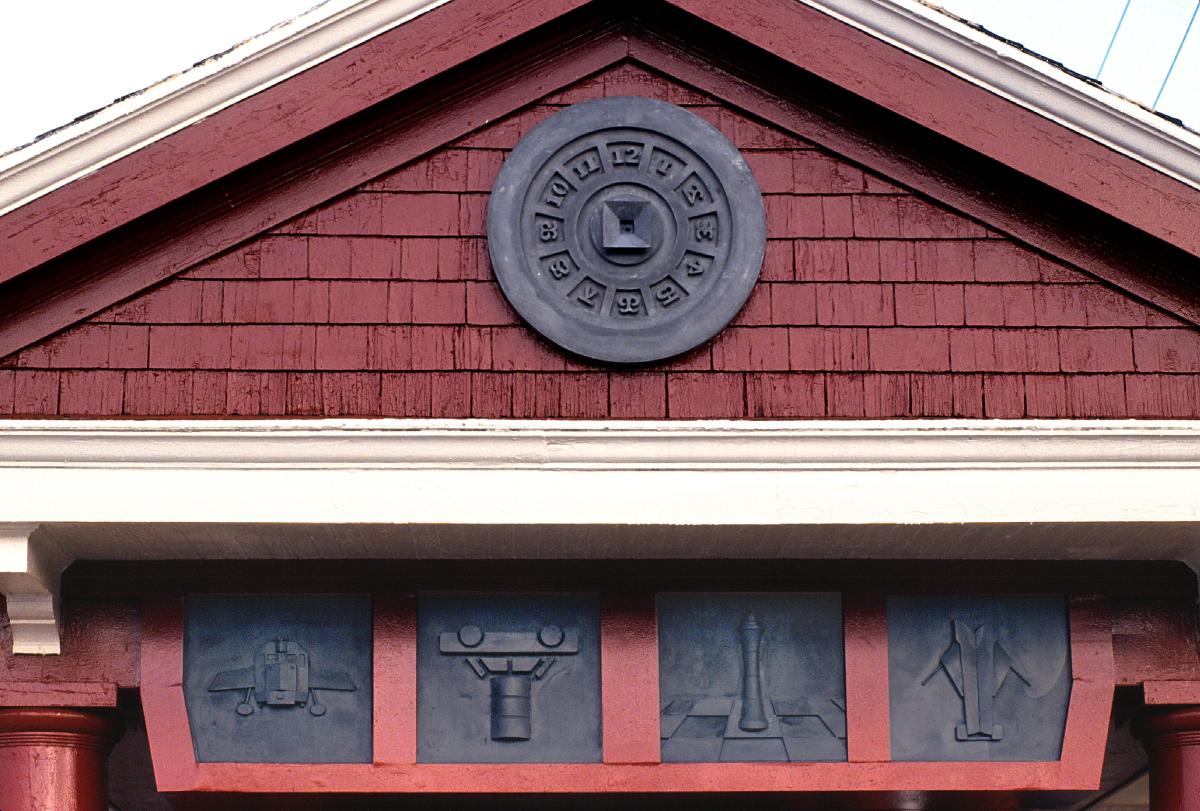 Artwork in cast cement by Brit Bunkley showing round medallions, symbolic of clocks, on the exterior of each end of the station that are set above framed icons representing local history and transportation.