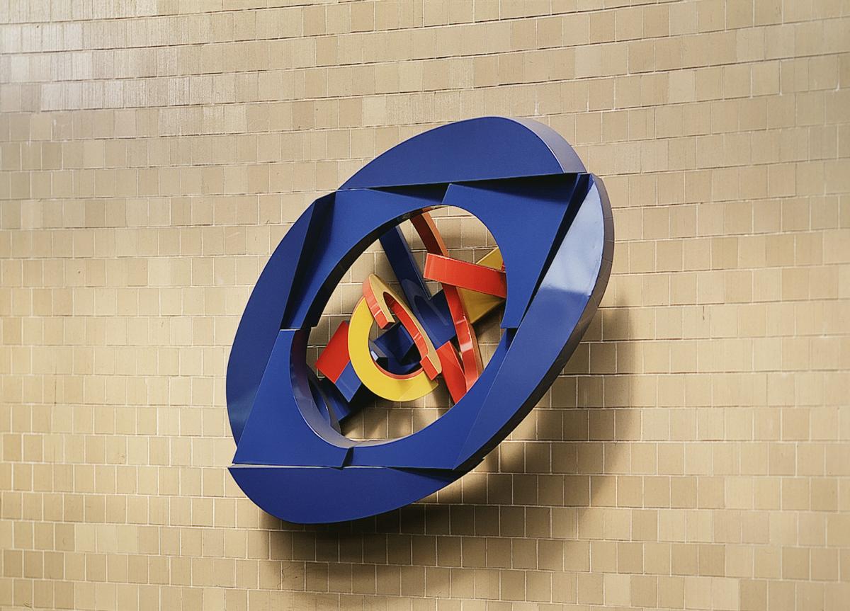 Artwork in painted aluminum by Sam Gilliam showing a large colorful circular sculpture on wall above the station entrance.