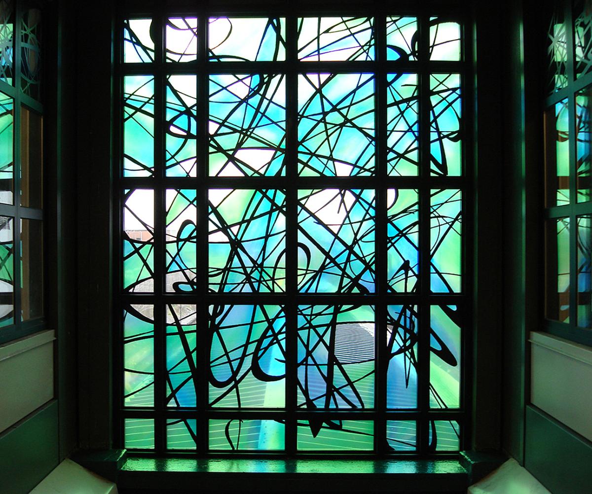 Artwork in laminated glass by Michael Ingui showing swirling black lines over a bright green and blue background.