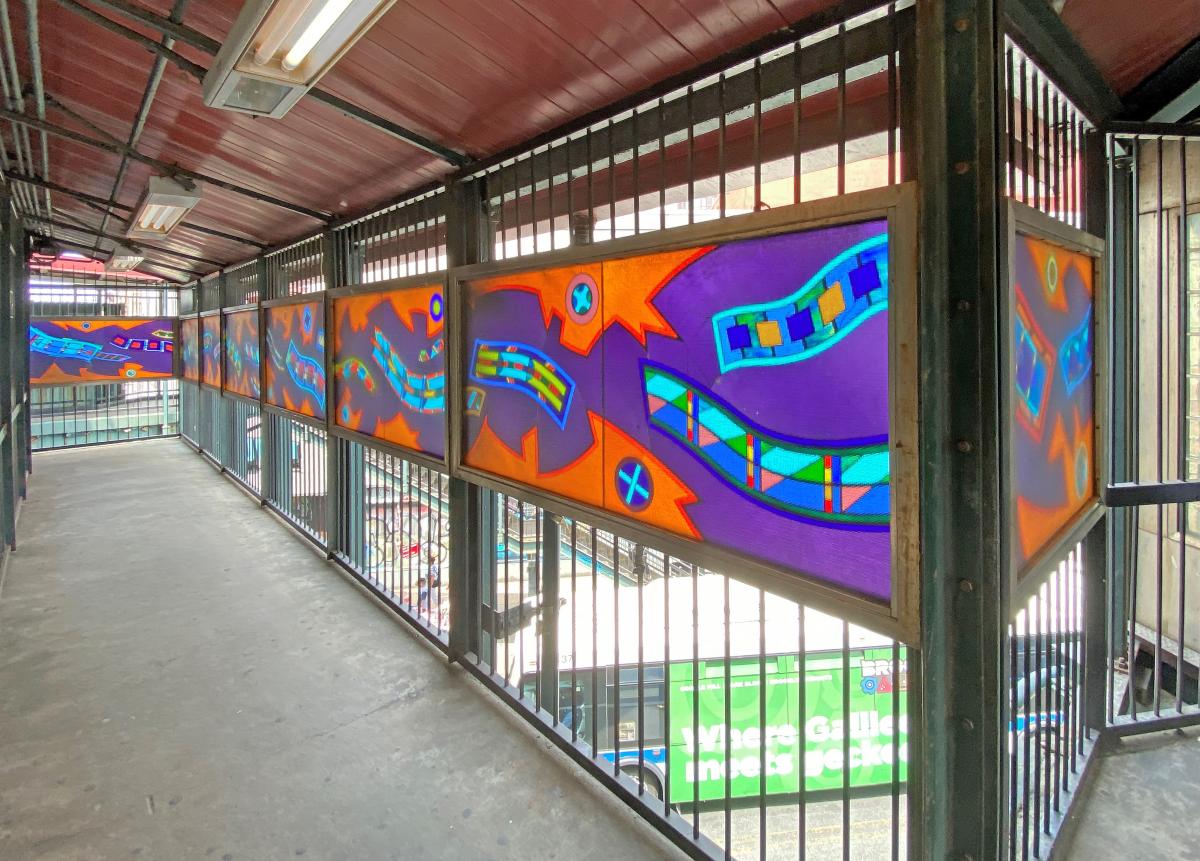 Artwork in laminated glass by Robin Holder showing colorful abstract shapes in purple, green and orange. 