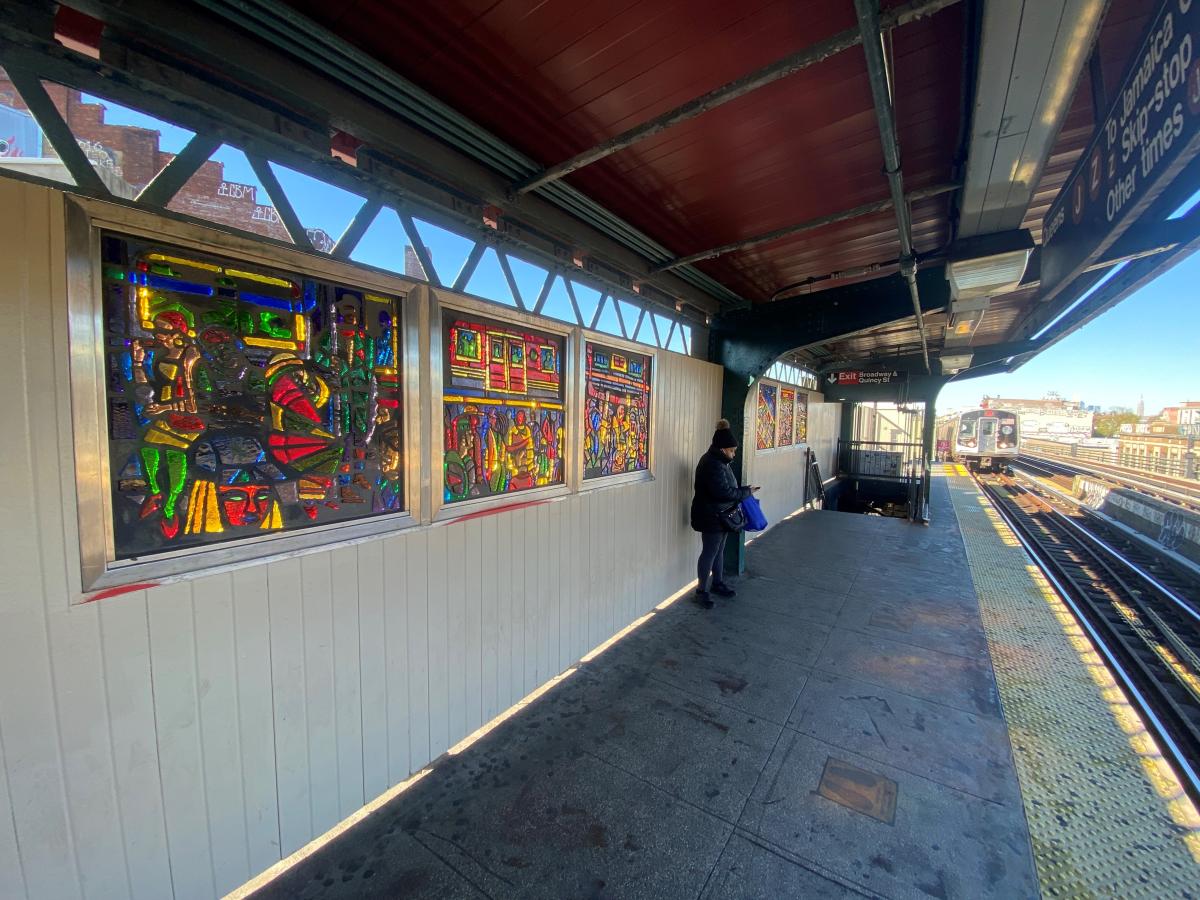 Artwork in faceted glass by Chris Wade Robinson showing colorful scenes of people interacting on trains and within the urban environment. 