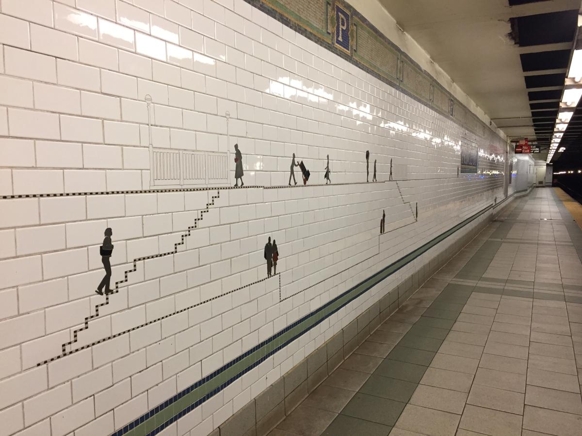 Artwork in steel, marble, and slate frieze on platform walls by Janet Zweig and Edward del Rosario showing almost two hundred small silver silhouettes of people hauling stuff with them as they walk the city streets. 