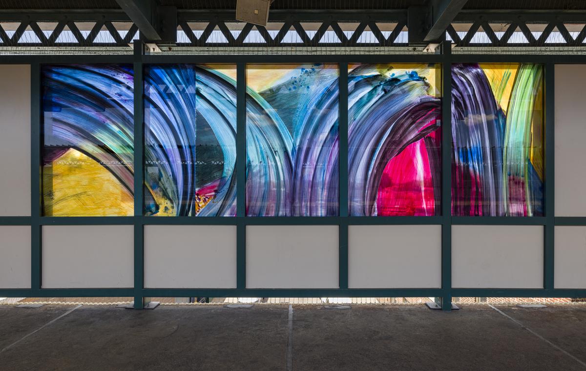 Glass artwork depicting large blue, yellow, and magenta brushstrokes.