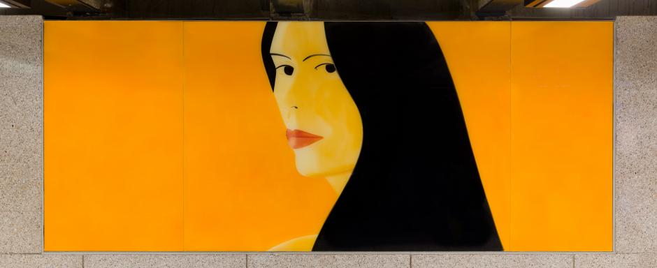 A permanent art installation on a station wall shows a woman on an orange background looking over her shoulder, with black hair framing her face.