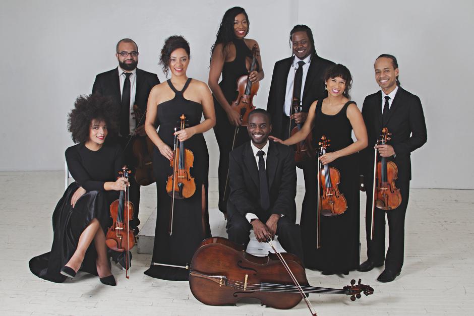 Four men and Four women in suits holding violins, violas and a cello.