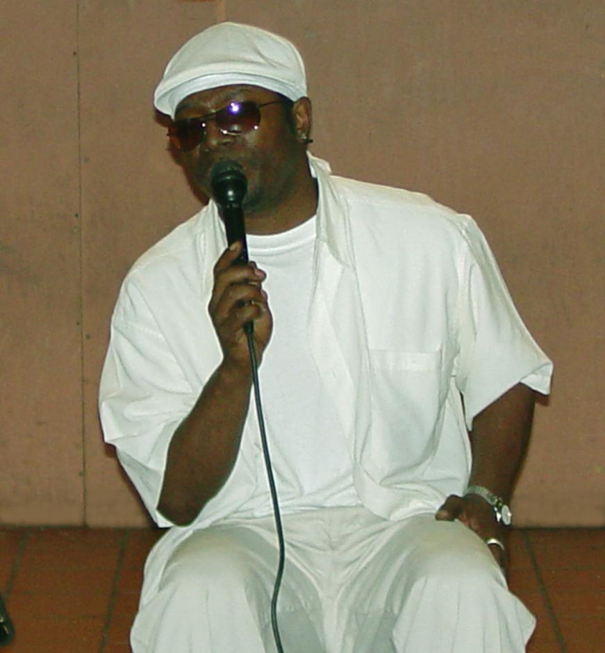 Man dressed in all white holding microphone.