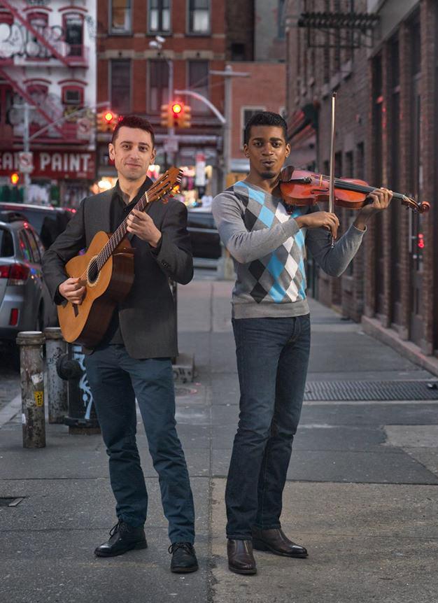 Two men on street with guitar and violin.