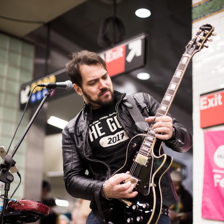 Man in leather jacket playing guitar.
