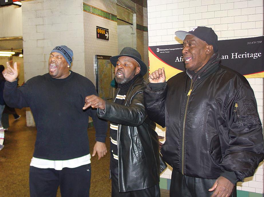 Three men in black jackets singing.
