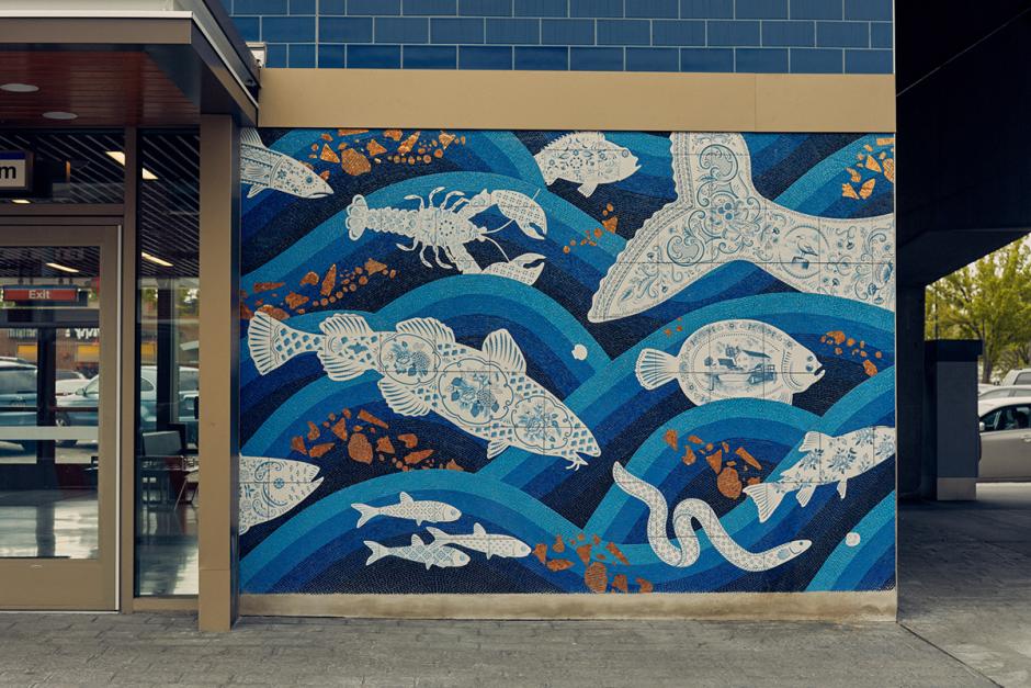 Photograph of station entrance exterior with a mosaic featuring waves of blue color with sea life swimming throughout.