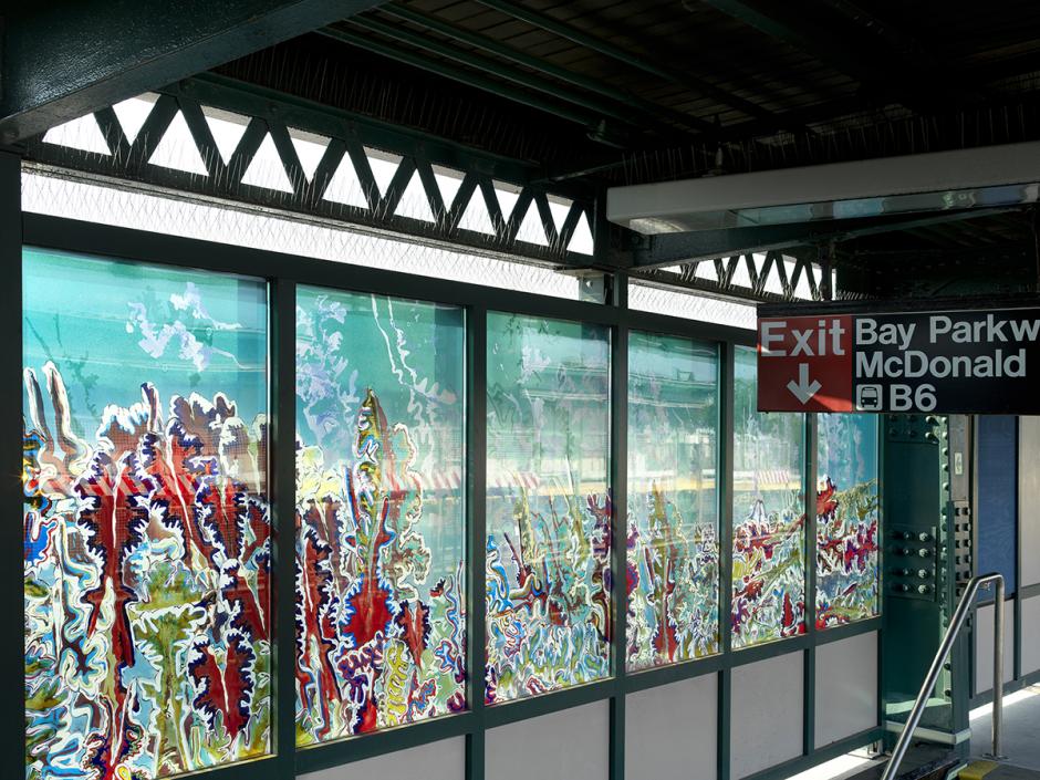 Photograph of station platform with Leslie Wayne’s glass artwork in station wall on left of photo, above exit stairs.  