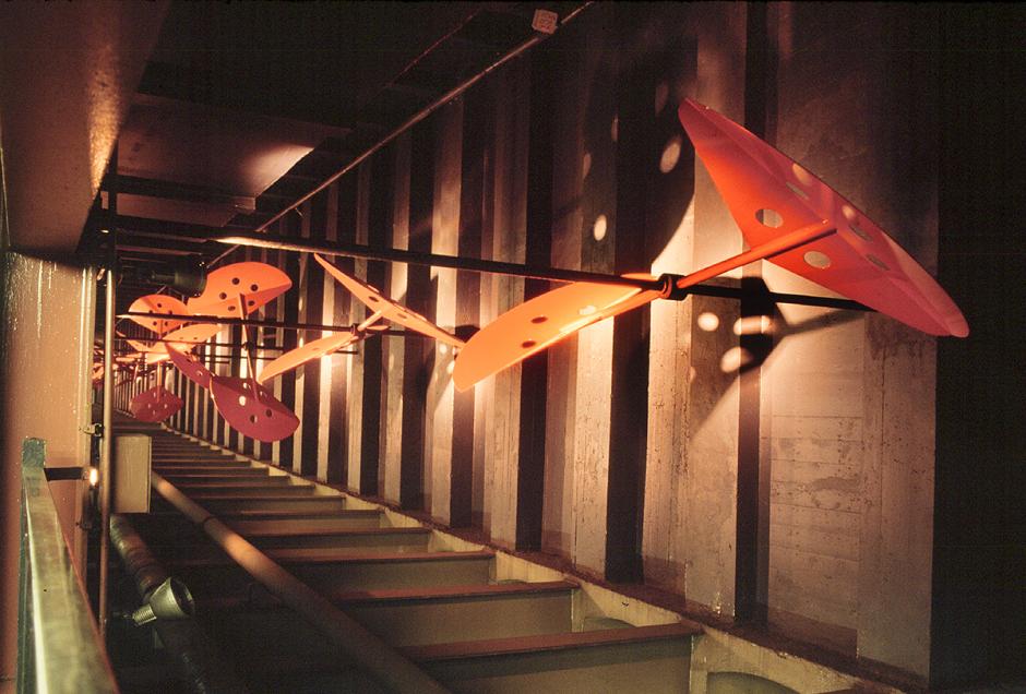 A Kinetic aluminum sculpture by David Provan showing A series of red wind paddles hanging between the walls of the station. 