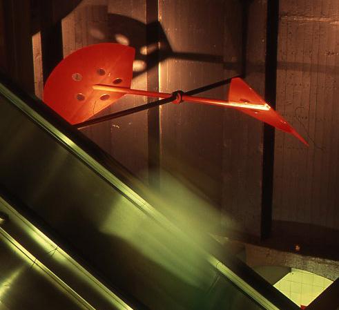 A Kinetic aluminum sculpture by David Provan showing A series of red wind paddles hanging between the walls of the station.