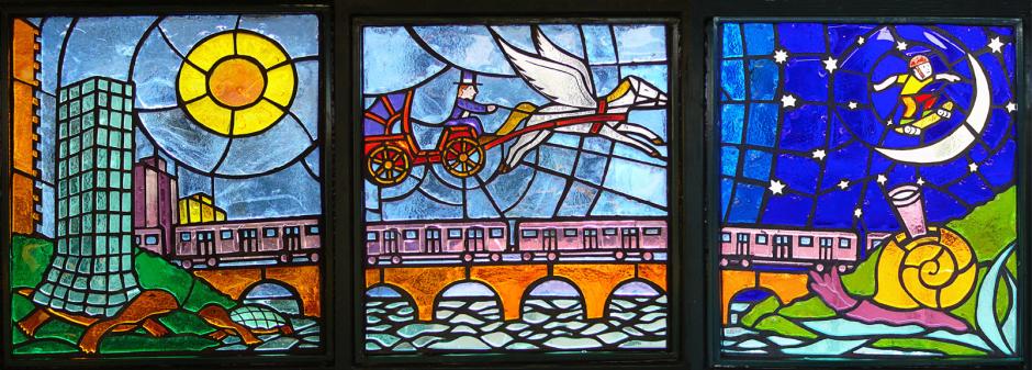 Artwork in faceted glass by Felipe Galindo showing urban, natural, surreal and historical scenes in colorful panels.