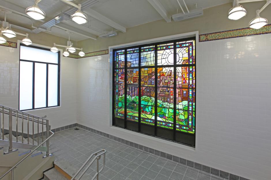 Artwork in faceted glass by William Low showing large colorful day and night city scenes over the stairwells.