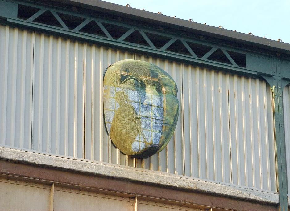 Three dimensional sculpture by Kathleen McCarthy in the form of a face projecting from an above ground station.