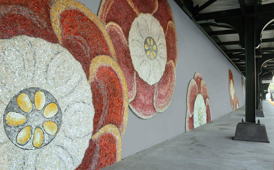 Artwork in glass mosaic by Nancy Blum showing large pink flowers on platform walls.