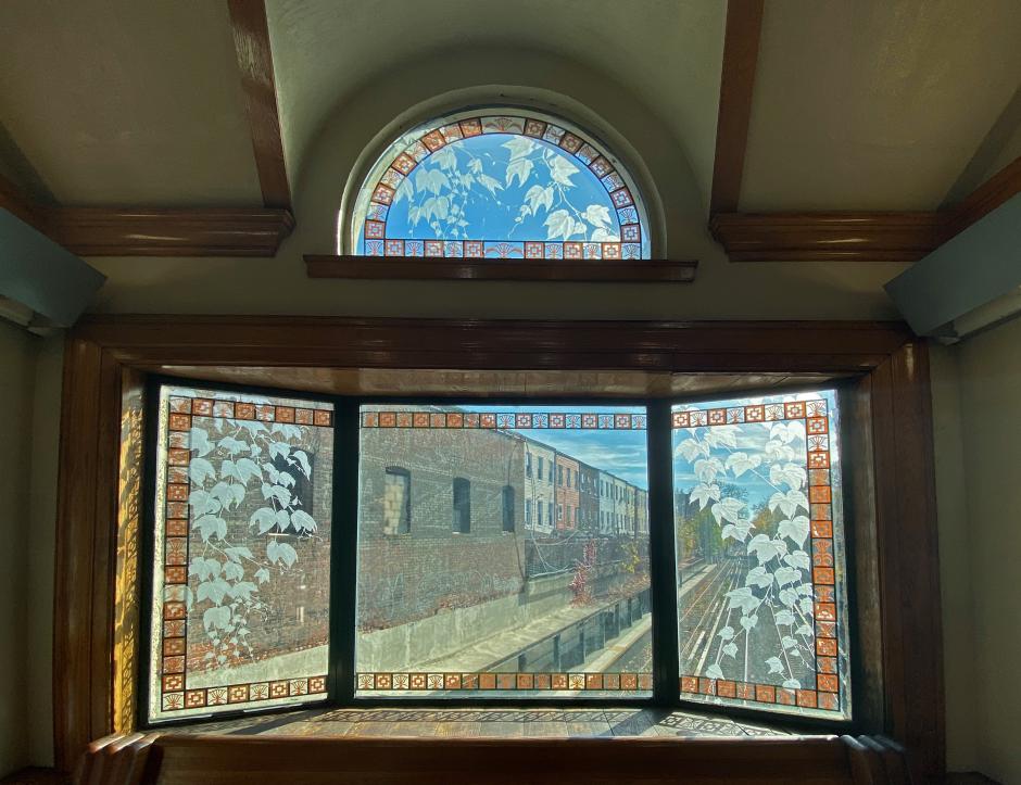 Artwork sandblasted glass by Patsy Norvell showing bay windows that are etched with floral imagery.