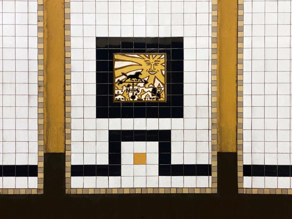 Artwork in ceramic tiles by Hugo Consuegra showing a series of ceramic tile panels on the platform walls and bronze medallions in station gates that revolve around the theme of the sun and moon. 