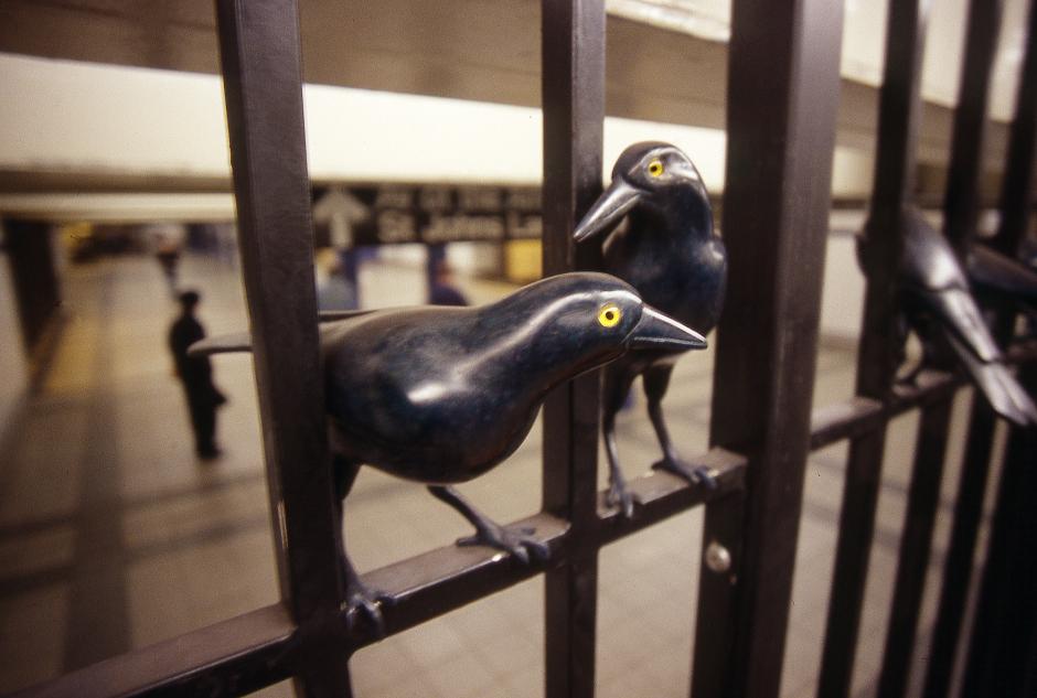 Artwork in bronze Walter Martin and Paloma Muñoz showing dozens of sculptural birds in different poses on the station gates and railings.  