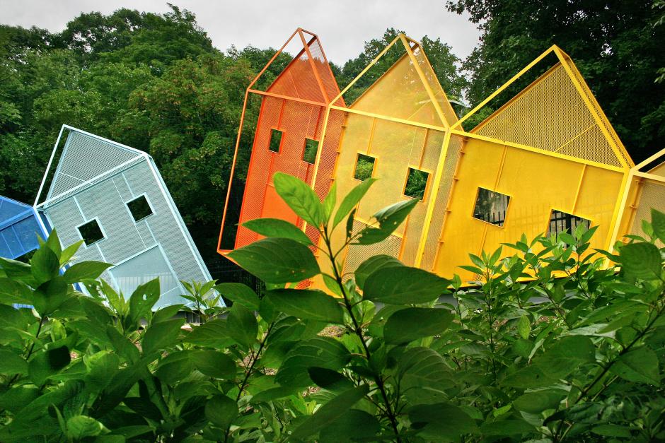 Artwork in perforated painted steel sculpture by Dennis Oppenheim showing low-relief, brightly colored metal sculptures in the shape of four houses. 
