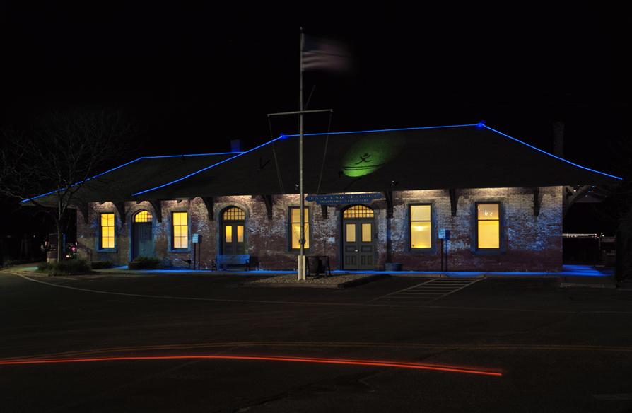 Artwork by Anita Thacher showing blue LED lighting and projection of a man and a canoe on the station facade and roof.  