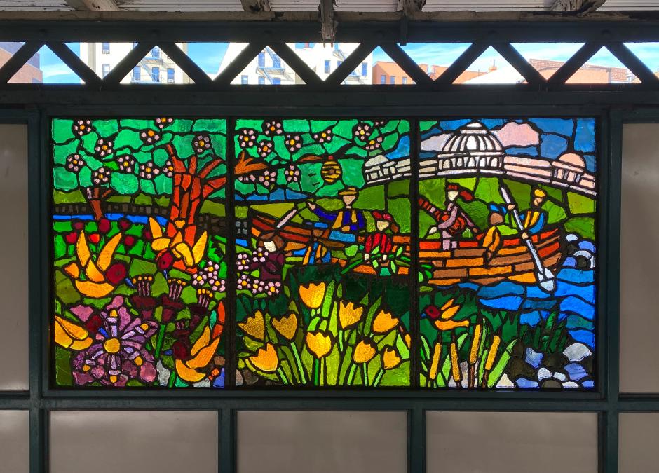 Artwork in faceted glass by Daniel del Valle showing a small group of figures canoeing passing by flowers and animals. 