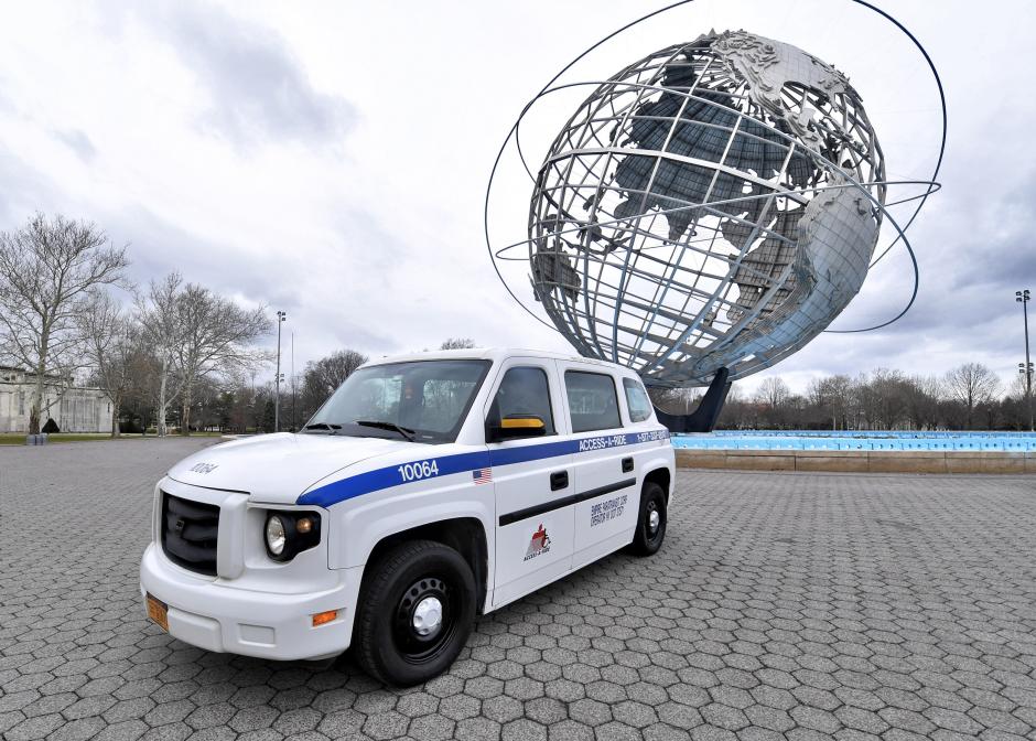A white Access-A-Ride van in front of the Unisphere at Flushing Meadows-Corona Park
