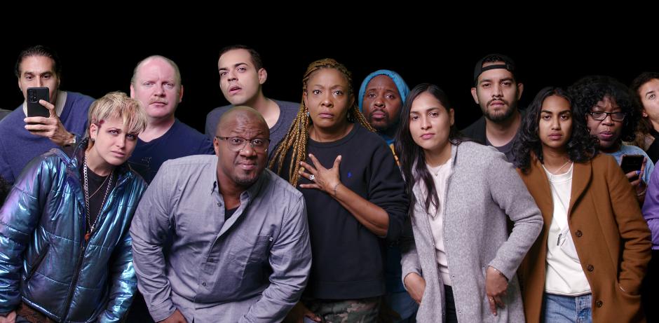 A group of people of diverse backgrounds and identities standing together in an all black studio