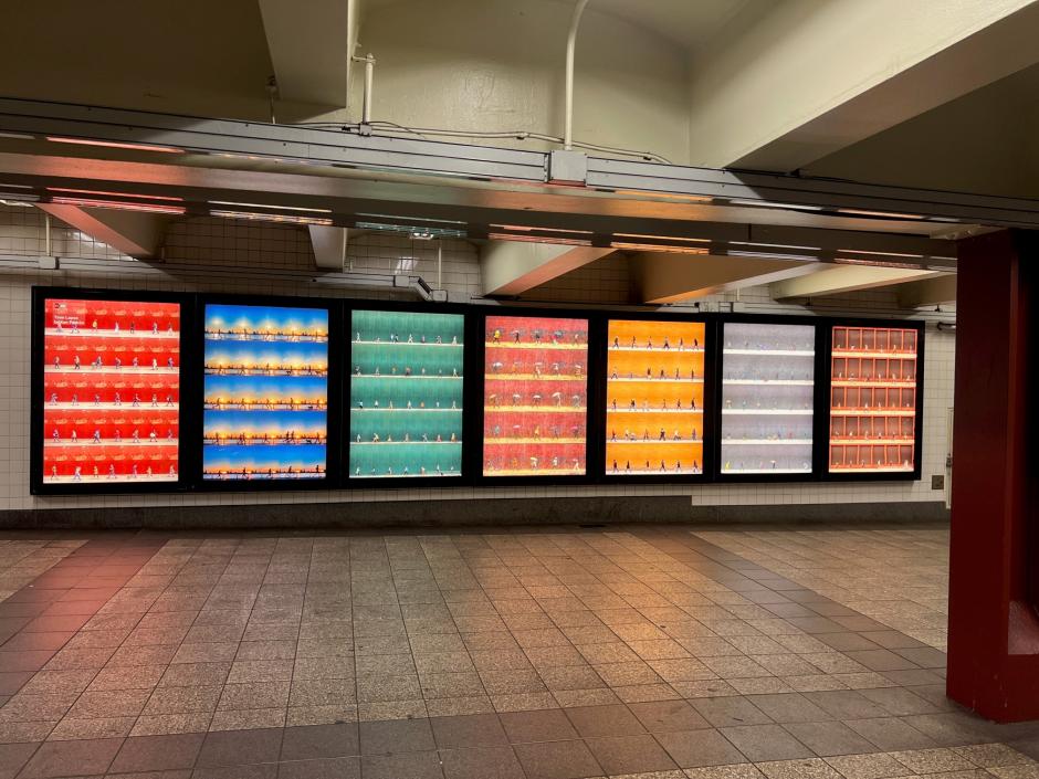 Photo lightboxes in a station environment exhibiting colorful serial photographs of people walking by the same wall. 
