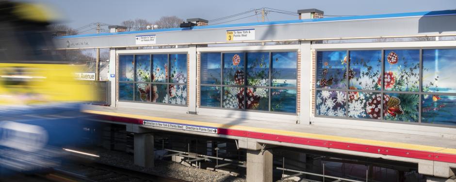 Glass artwork on a station platform with depictions of flowers and butterflies.