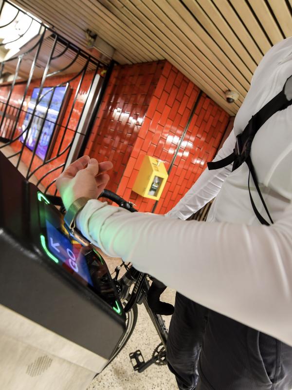 A woman uses a smart watch to pay the fare with an OMNY contactless reader at a subway turnstile.